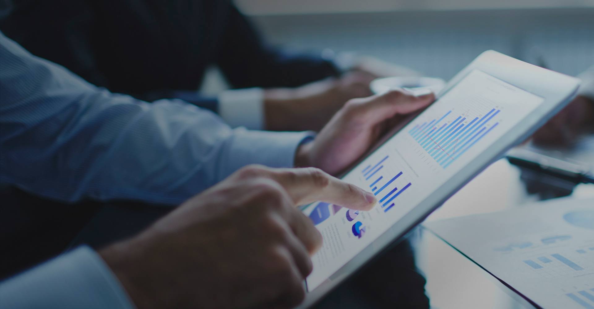 close-up of man viewing financial graphs on mobile tablet